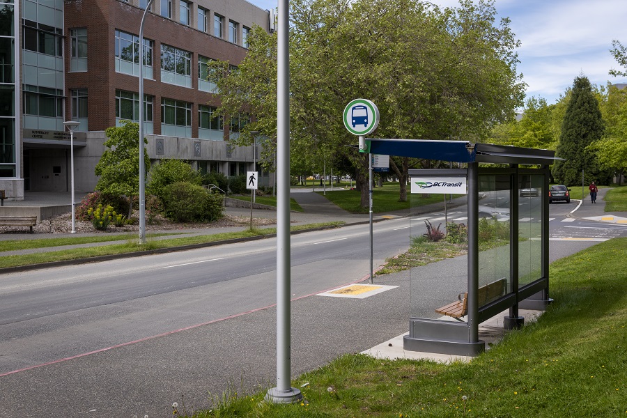 A bus shelter in a semi-urban, grassy, roadside area